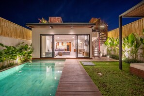 A modern house with a swimming pool, a wooden deck, and a well-maintained garden.
