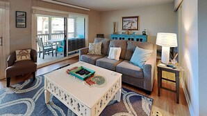 A living room with a sofa, armchair, coffee table, and a small side table with a lamp. - Inlet Point 15B, Beautifully Furnished Condo, Near Beach & Creek (Pawleys Island)