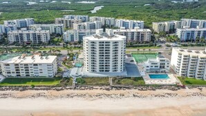 Ein hoch aufragender Wohnkomplex mit mehreren Wohngebäuden, einem Innenhof und Blick auf einen Strand.