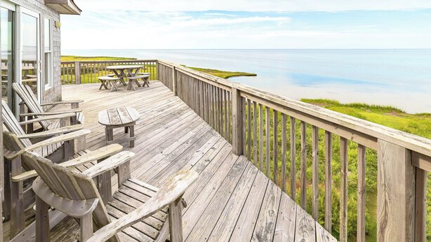 A wooden deck with outdoor seating and a view of the ocean. - Windscape Soundfront in Frisco Incredible Views 400ft to Beach Access! (Frisco)