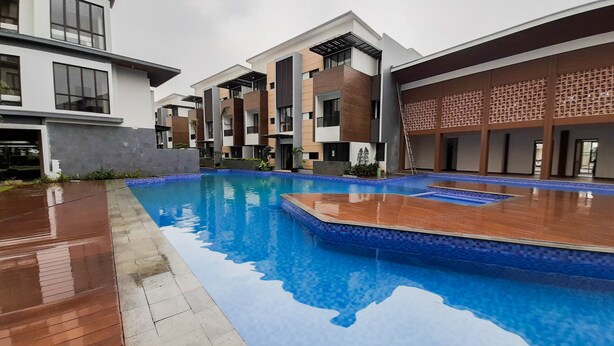 Um edifício moderno com piscina, combinando painéis de vidro e madeira, e um deck revestido com azulejos.