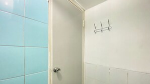 A bathroom with light blue tiles, a white door, and a towel rack on the wall.