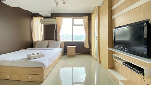 A modern hotel room with a bed, a TV, a bedside table, and a window with curtains.