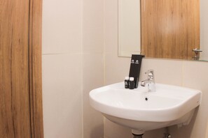 Bathroom features a sink and mirror, with a tiled wall and door.