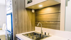 A modern kitchen with a built-in sink, wooden wall paneling, and a countertop. - Comfort And Best Choice 2Br At Bintaro Icon Apartment (South Tangerang)