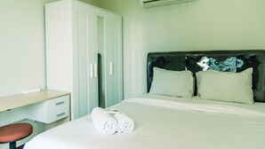 Una habitación de hotel con una cama, un escritorio, una silla y un armario.