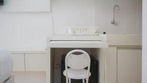 Eine kleine Küchenzeile mit einem weißen Stuhl, einem Spülbecken und einem Wasserhahn.