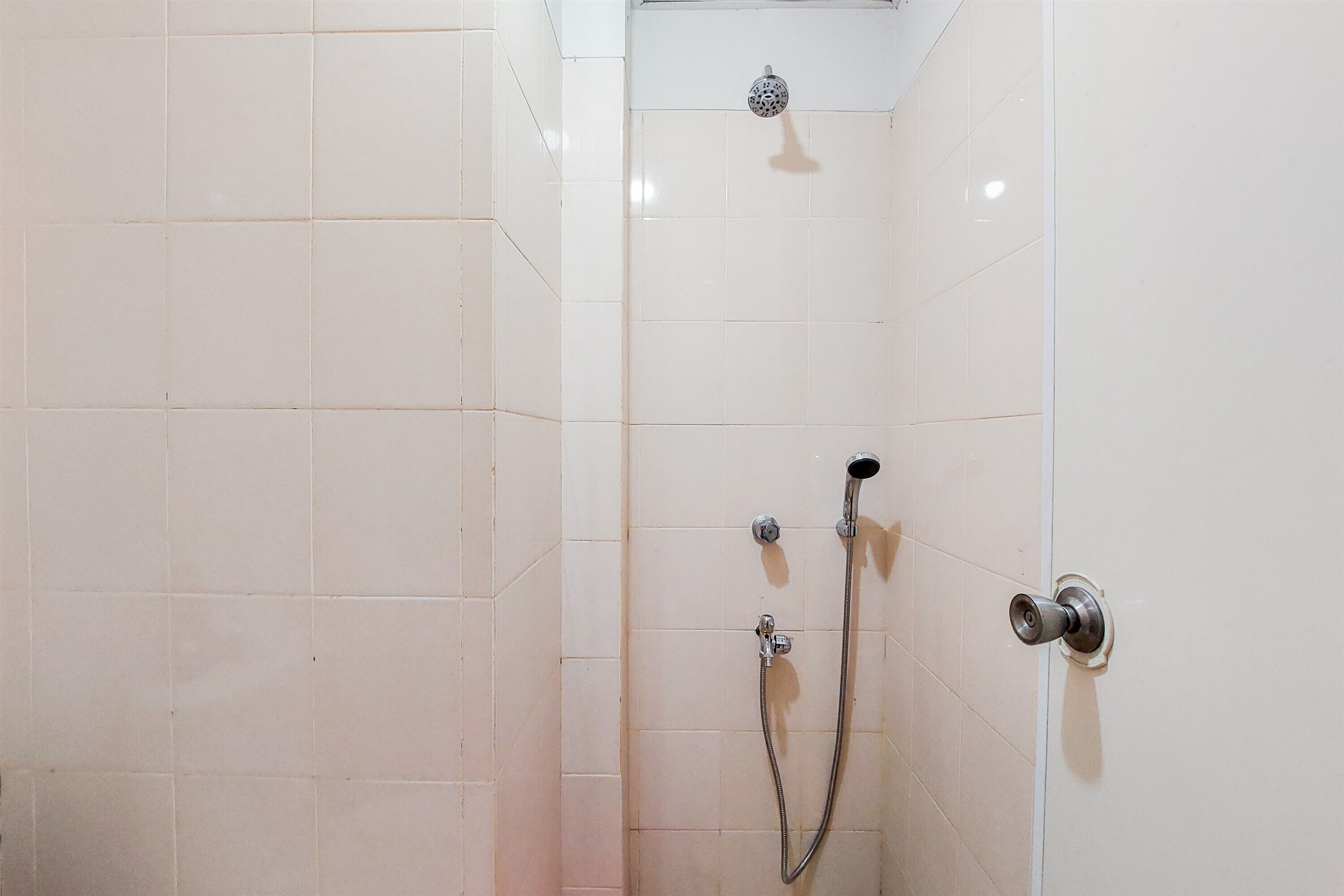 A shower with a handheld showerhead and a fixed wall-mounted showerhead.