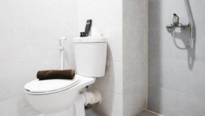 Eine weiße Toilette mit Handtuch auf dem Sitz, einem Papierhandtuchhalter und einer Toilettenpapierrolle.