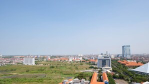 Eine Stadtansicht mit einer Mischung aus Wohn- und Geschäftsgebäuden, darunter ein markantes Hochhaus und ein Stadion.