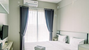 Une chambre d’hôtel équipée d’un lit, d’un bureau avec un ordinateur, d’une télévision et d’un appareil de climatisation.