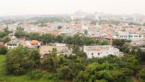 A densely packed urban area with numerous buildings, some with red roofs, surrounded by greenery. - Great Location And Simply Studio Room At Bassura City Apartment (Jakarta)