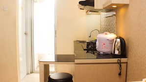 A compact kitchen with a stove, sink, and a small countertop. - Great Location And Simply Studio Room At Bassura City Apartment (Jakarta)