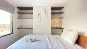 A hotel room with a neatly made bed, a bedside lamp, and artwork on the wall.
