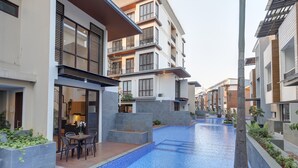 Un moderno edificio residencial con piscina, balcones y un jardín bien cuidado.
