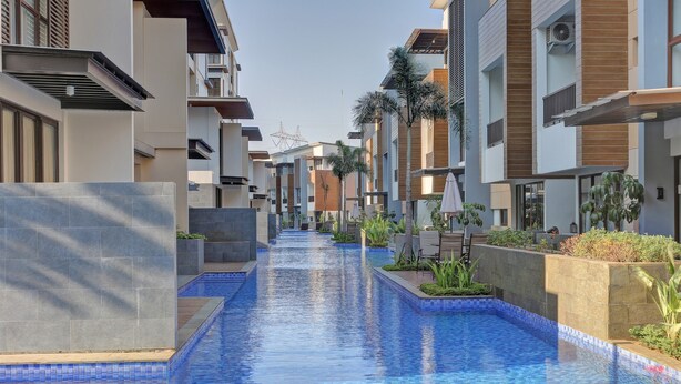 Un moderno complejo residencial con piscina central, rodeado de edificios de varios pisos con balcones y zonas de estar al aire libre.