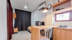Cocina compacta con comedor, refrigerador empotrado, ventana y un reloj en la pared.