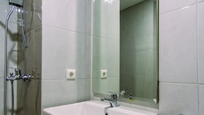 A bathroom with a white sink, a mirror, and a shower with a handheld showerhead. - Comfort Studio Apartment At Padina Soho Residence (Tangerang)