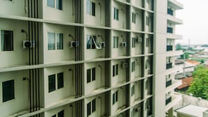 A multi-story building with a uniform facade, featuring evenly spaced windows and air conditioning units. - Comfort Studio Apartment At Padina Soho Residence (Tangerang)