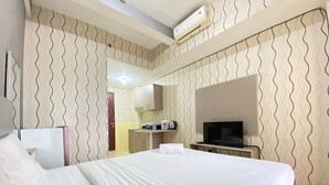 Hotellihuone, jossa on sänky, televisio, pieni keittiö ja ilmastointilaite.