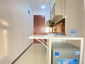 A compact kitchen with a built-in refrigerator, a sink, and a water dispenser.