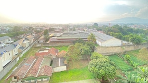A residential area with houses, a large building with a flat roof, and a green field. - Comfy Studio At Gateway Pasteur Apartment (Cimahi)