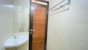 A bathroom with a wooden door, a sink, and a mirror. - Comfy Studio At Gateway Pasteur Apartment (Cimahi)