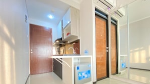 A modern hotel corridor with a wooden door, a kitchenette area, and a glass elevator. - Comfy Studio At Gateway Pasteur Apartment (Cimahi)