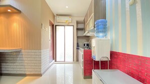 A kitchen with a water dispenser, a refrigerator, and a red brick accent wall. - Spacious Studio Furnished Apartment At Gateway Ahmad Yani Cicadas Bandung (Bandung)