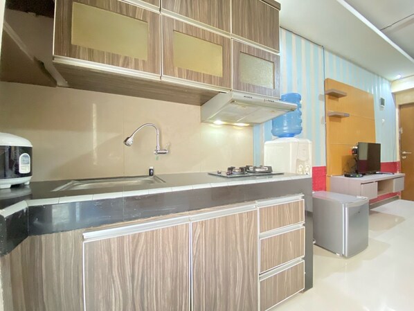 A modern kitchen with a built-in stove, a sink, and a water dispenser. - Spacious Studio Furnished Apartment At Gateway Ahmad Yani Cicadas Bandung (Bandung)