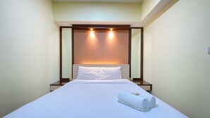 A hotel room with a neatly made bed, a headboard with integrated lighting, and a mirror on the wall. - Spacious And Modern 2Br At Braga City Walk Apartment (Bandung)