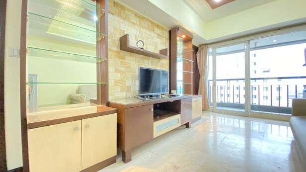 A modern living room with a flat-screen TV, glass shelving, and a large sliding glass door leading to a balcony. - Spacious And Modern 2Br At Braga City Walk Apartment (Bandung)