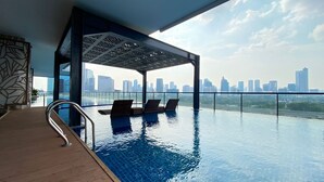 Ein Innenpool mit Infinity-Kante, Liegestühlen und Blick auf die Stadtlandschaft.