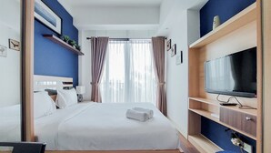 A hotel room with a bed, a TV, and a desk. - Nice And Elegant Studio At Tree Park City Bsd Apartment (South Tangerang)