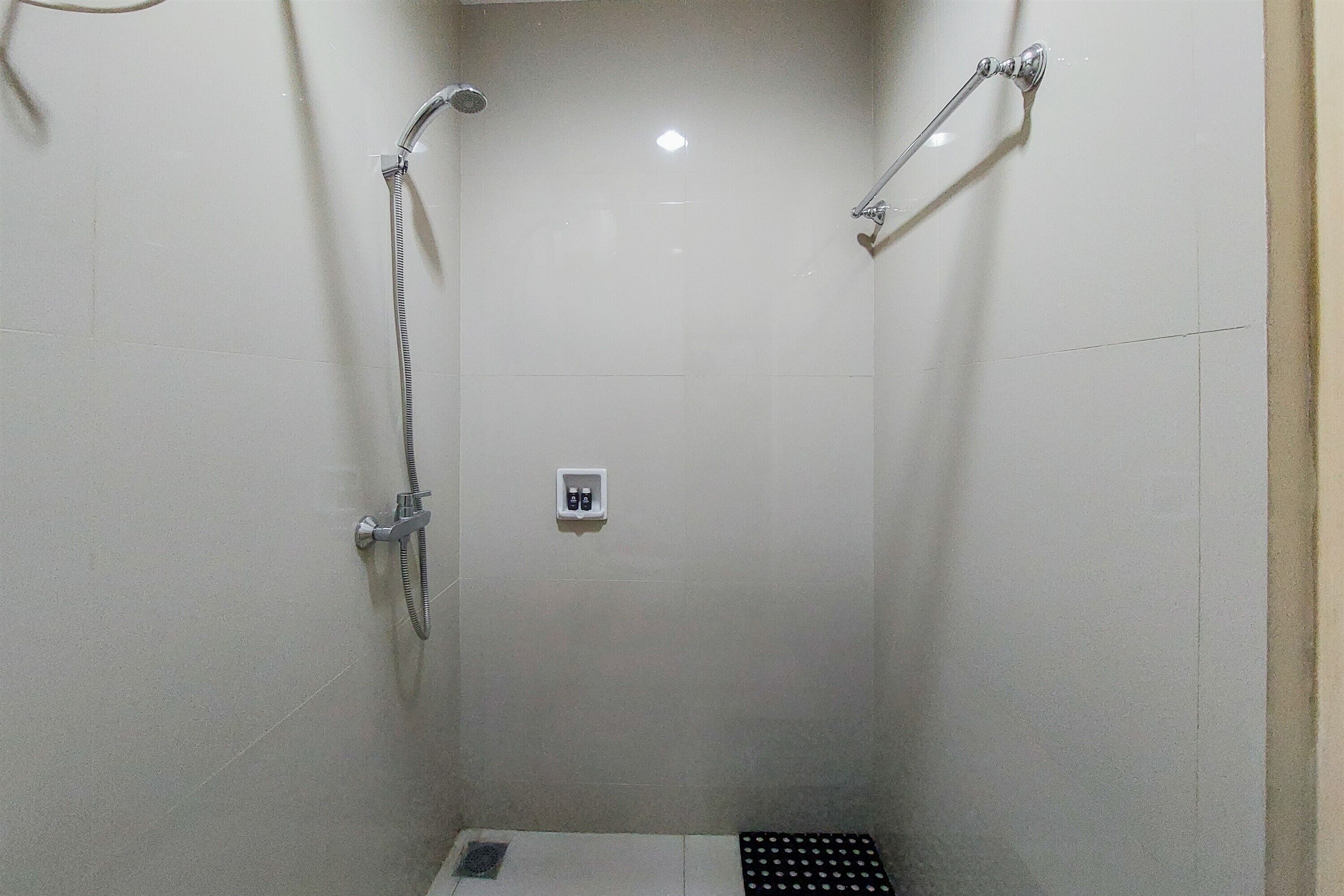 A small, enclosed shower area with a handheld showerhead and a wall-mounted faucet.