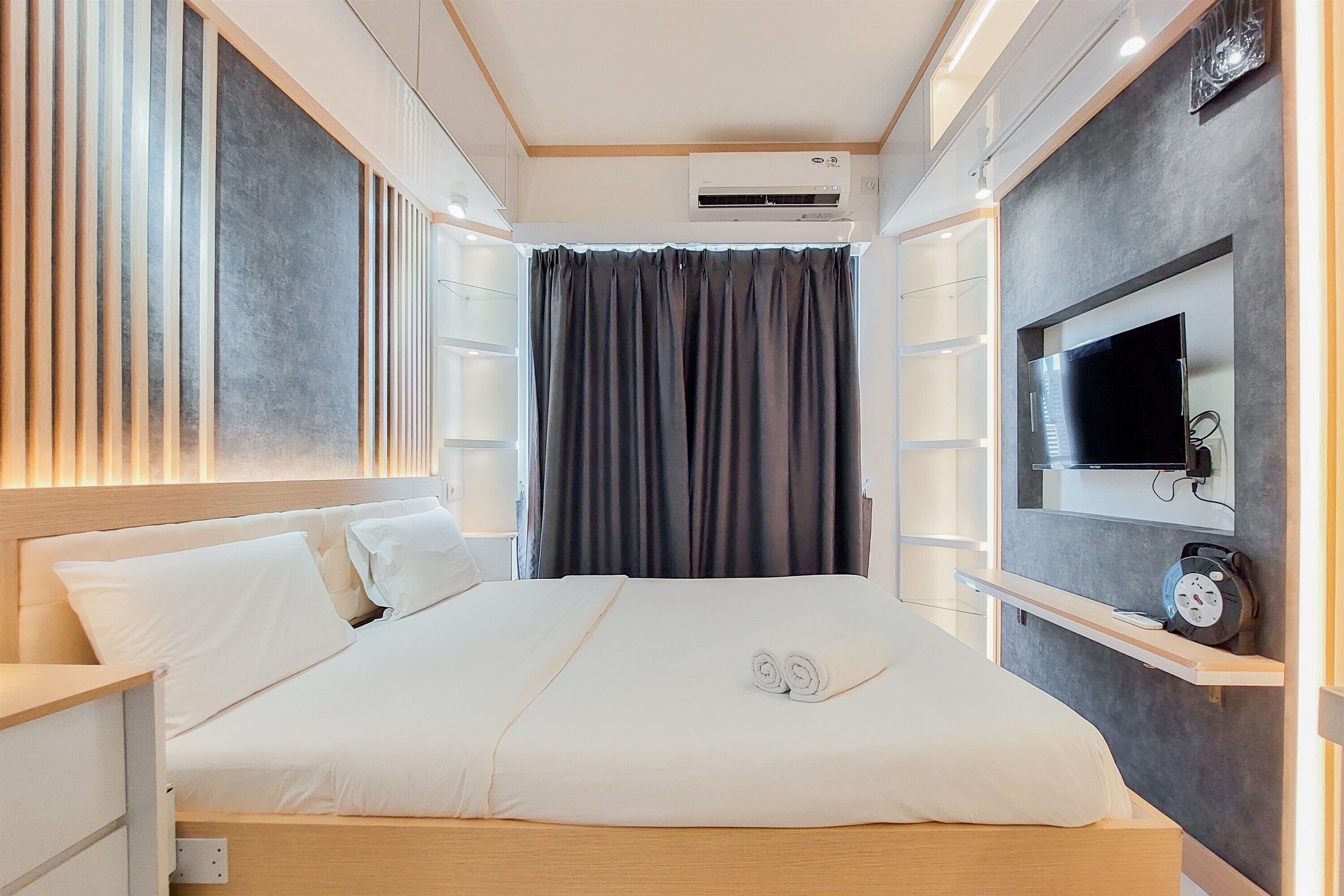 Une chambre d’hôtel équipée d’un lit, d’un téléviseur fixé au mur, d’une horloge et d’un appareil de climatisation.