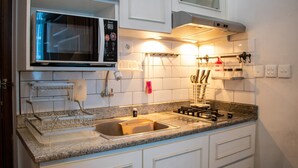 A modern kitchen with white cabinets, a granite countertop, a built-in microwave, and a stainless steel sink. - Nice And Cozy 1Br With Extra Room Apartment At Capitol Park Residence (Jakarta)