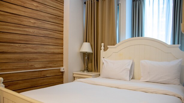 A neatly made bed with white linens, a wooden headboard, and a bedside lamp. - Nice And Cozy 1Br With Extra Room Apartment At Capitol Park Residence (Jakarta)