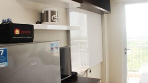 Un angolo cottura con frigorifero, macchina del caffè e una borsa da viaggio sul ripiano.