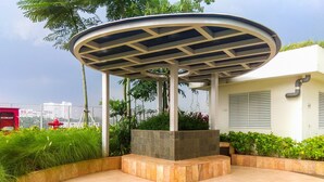 A covered pavilion with a tiled floor, surrounded by greenery and a white fence. - Best Choice And Warm Studio At Springlake Summarecon Bekasi Apartment (Bekasi)