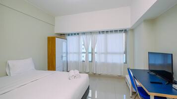 A hotel room with a bed, a desk, a television, and a window with curtains.