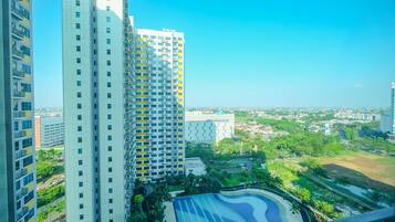 A high-rise building with multiple floors, a swimming pool, and surrounding greenery.