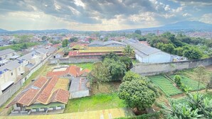 A residential area with houses, a large building, and a fenced garden. - Cozy Studio Apartment At Gateway Pasteur (Cimahi)