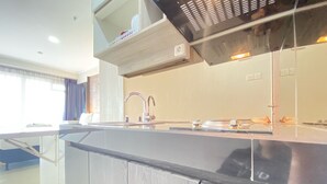 A modern kitchen with a stainless steel countertop, a built-in oven, and a range hood. - Cozy Studio Apartment At Gateway Pasteur (Cimahi)