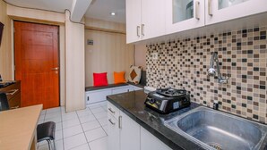 A compact kitchen with a black countertop, a stainless steel sink, and a portable gas stove. - Cozy And Warm 2Br At Kebagusan City Apartment (Jakarta)