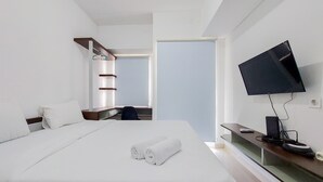 A modern hotel room with a large bed, a flat-screen TV, a desk, and a chair. - Fancy And Nice Studio Apartment At Serpong Garden (Cisauk)