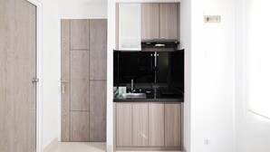 A compact kitchen with a built-in oven, a sink, and wooden cabinetry. - Cozy Living Studio At Taman Melati Surabaya Apartment (Surabaya)