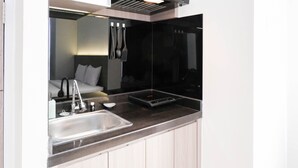 A modern kitchen with a stainless steel sink, a black induction cooktop, and a sleek countertop. - Cozy Living Studio At Taman Melati Surabaya Apartment (Surabaya)