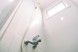 Enjoy a refreshing shower in this bathroom with a showerhead mounted on the wall and a small window for natural light.