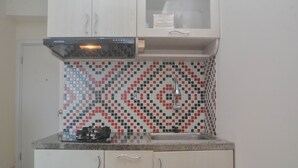 A kitchen with white cabinets, a patterned backsplash, and a stainless steel sink. - Comfy And Best Deal 2Br At Green Pramuka City Apartment (Jakarta)